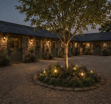 Computer-generated impression of the courtyard at dusk, lit doorways around a gravelled yard